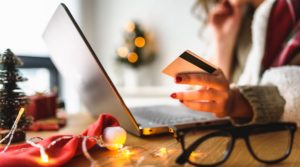 A woman is on her laptop entering her credit card info, exposing herself to cybersecurity threats during the holidays.