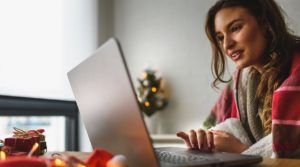 A woman is on her laptop online shopping, exposing herself to cybersecurity threats during the holidays.